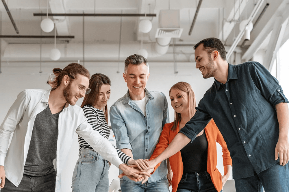 A happy team putting their hands together in celebration