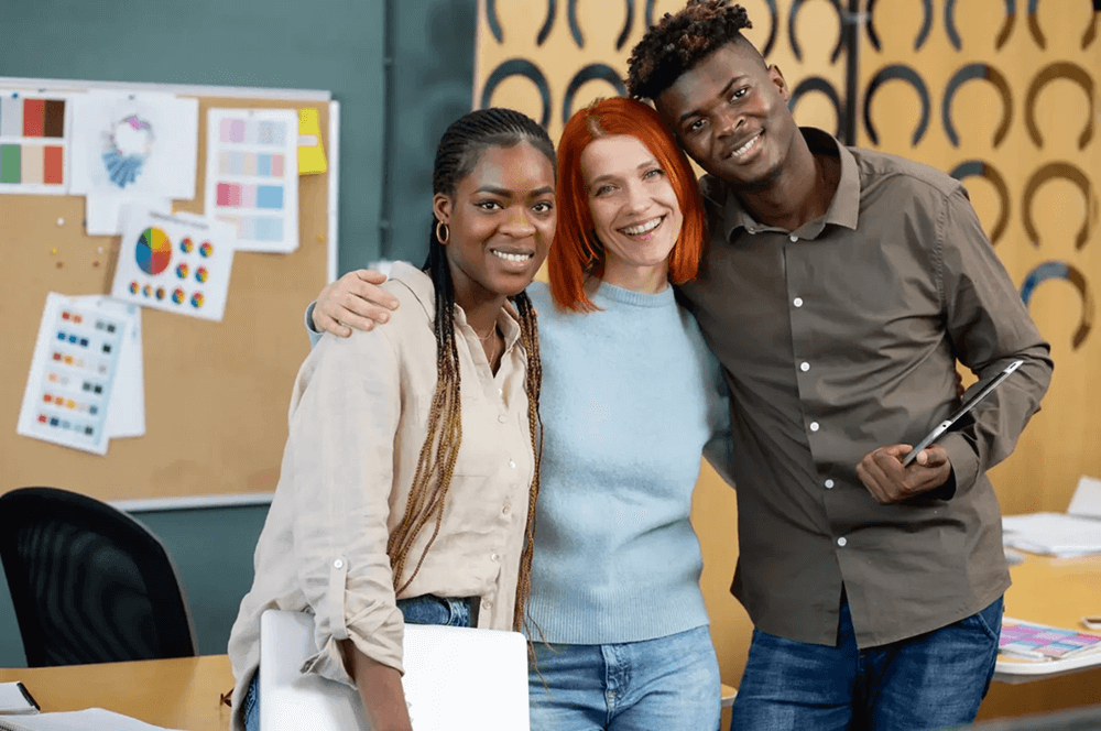 Two happy business students with their language teacher in the office