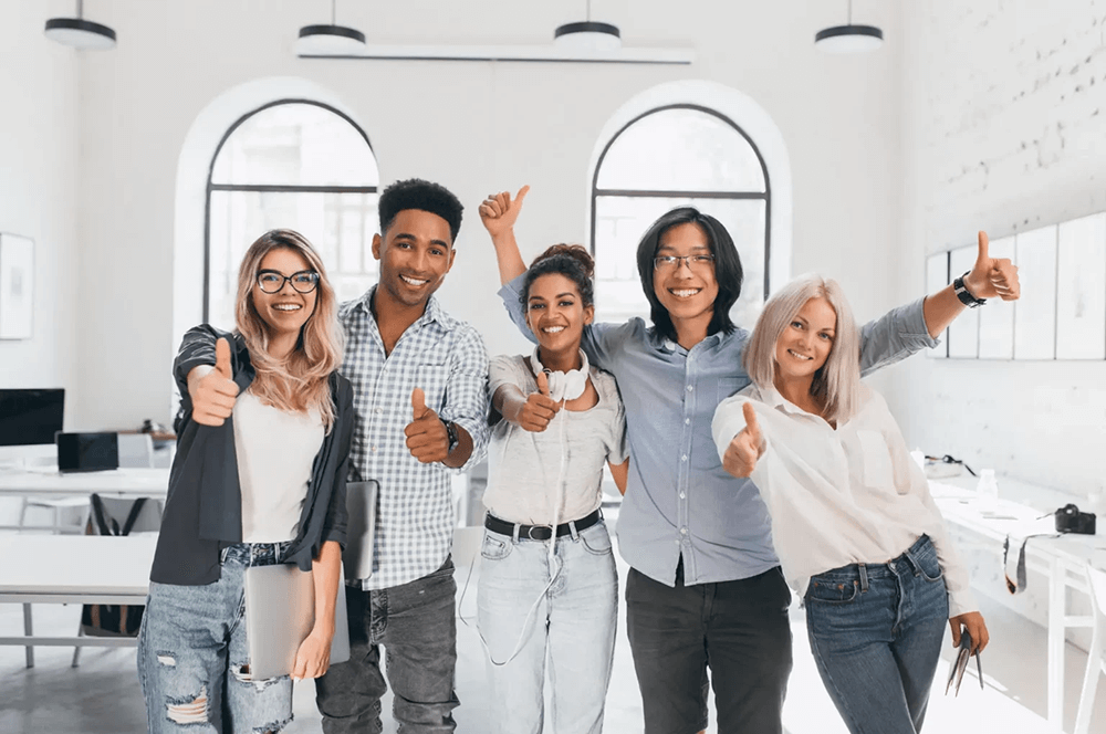 A happy group of employees giving a thumbs-up for their business language class in the office
