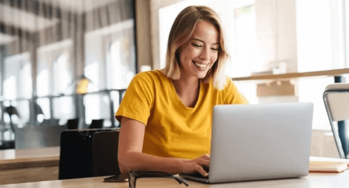 A student smiling while doing her online learning course with her PC in front of her