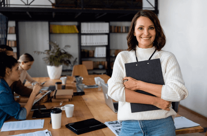 Manager smiling at the camera with her team members in the office