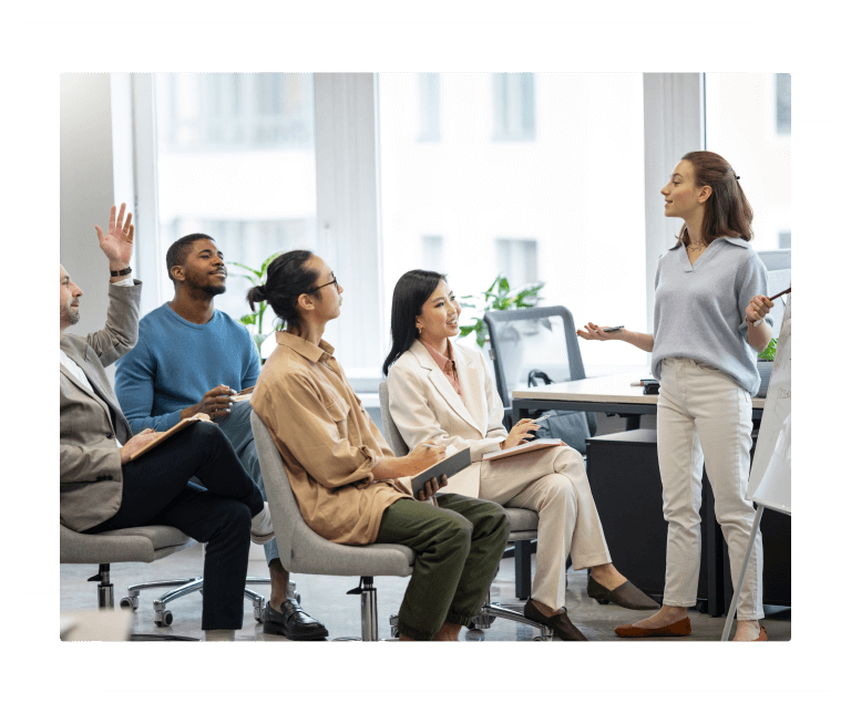 A group of colleagues attending an in-person corporate language course at their office with a young teacher