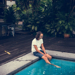 Homme assis au bord d’une piscine, illustrant la détente et la flexibilité des cours d’espagnol en ligne.