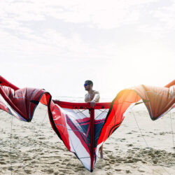 Homme installant son équipement de kitesurf sur une plage après avoir suivi un cours d’espagnol en ligne avec un tuteur Edlingo, illustrant la liberté d’apprendre tout en profitant de ses loisirs.