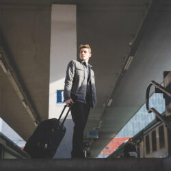 Homme avec une valise dans une gare après avoir suivi un cours de français en ligne avec un tuteur Edlingo.