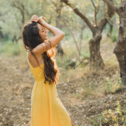 Jeune femme en robe jaune se détendant dans un champ après avoir suivi un cours de français en ligne avec un tuteur Edlingo.