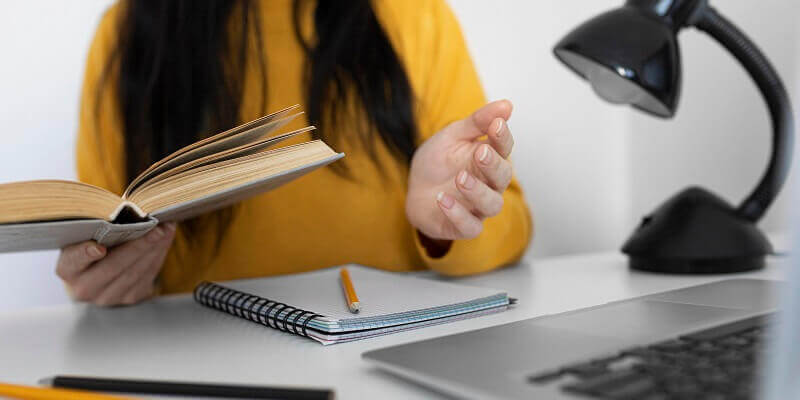 Femme étudiant l’anglais avec un livre et un ordinateur portable